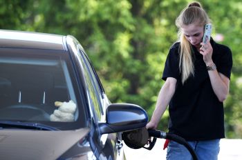 Женщина заправляет автомобиль на автозаправочной станции 