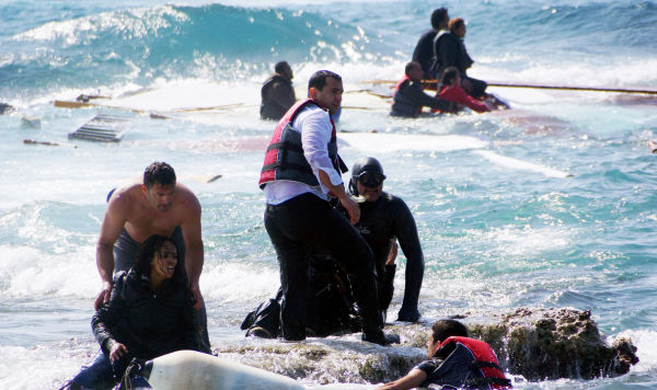 Местные жители помогаю беженцам выбраться на берег после крушения судна с мигрантами около острова Родос, Греция, 20 апреля 2015