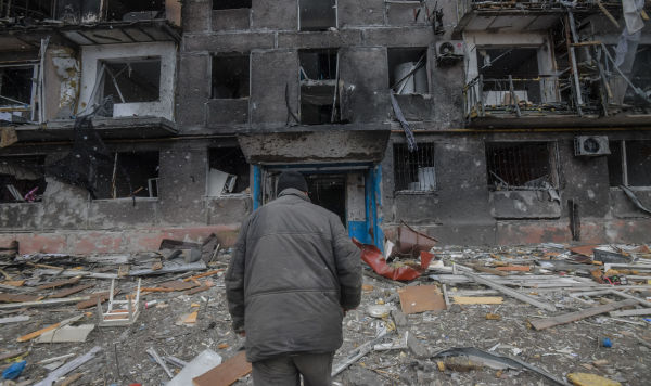 Житель идет к подъезду разрушенного дома на окраине Мариуполя