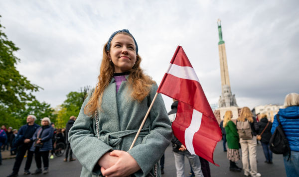 Девушка с флагом Латвии у памятника Свободы