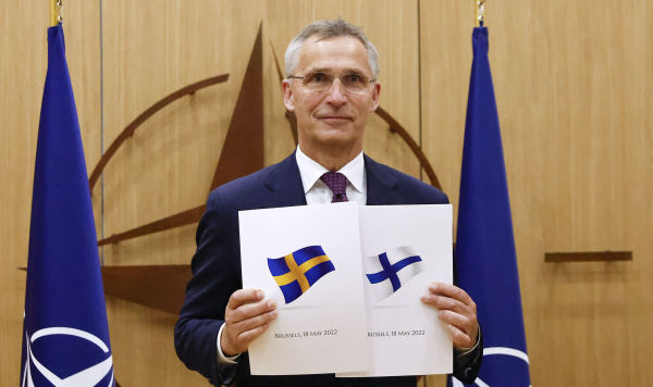 Генеральный секретарь НАТО Йенс Столтенберг позирует с заявочными документами по заявке Швеции и Финляндии на членство в НАТО, 18 мая 2022
