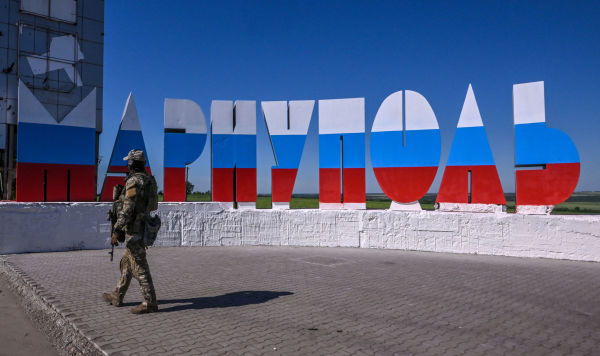 Российский военнослужащий на фоне надписи "Мариуполь"