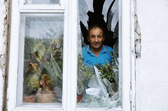 Мужчина смотрит из окна своего дома в Куйбышевском районе Донецка, получившего повреждения в результате обстрела со стороны ВСУ