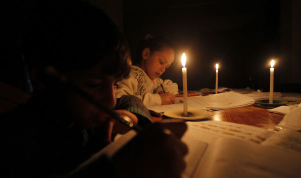 Дети делают домашнее задания при свечах 