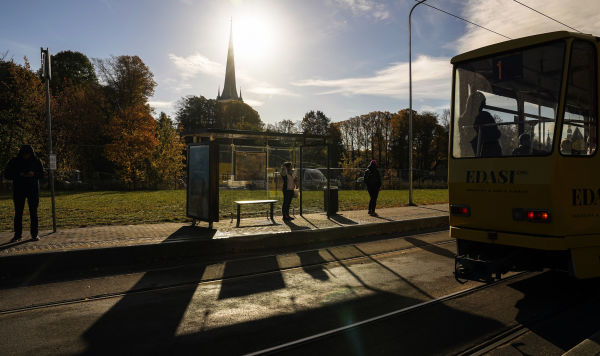 Люди ждут трамвая на остановке в Таллинне, Эстония