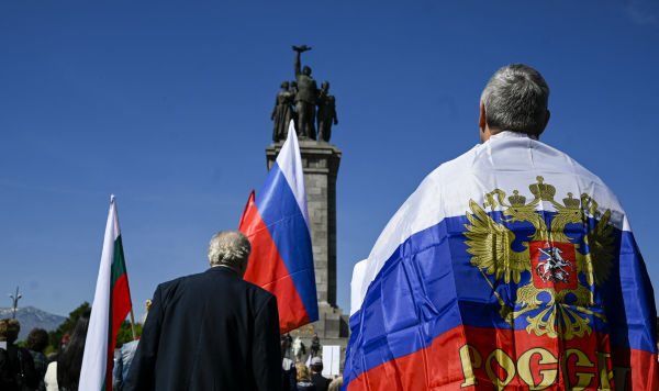 Мужчина с флагом России стоит перед памятником Советской Армии в Софии, Болгария
