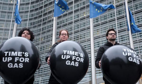Люди держат воздушные шары с надписью «время для газа вышло» возле здания Европейской комиссии в Брюсселе