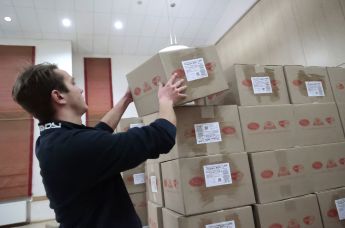 Волонтер складывает коробки с гуманитарным грузом для детей Донецка