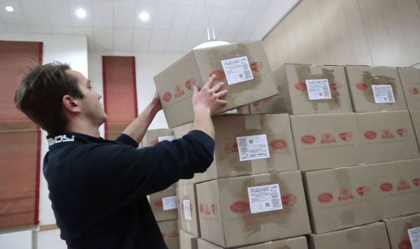 Волонтер складывает коробки с гуманитарным грузом для детей Донецка
