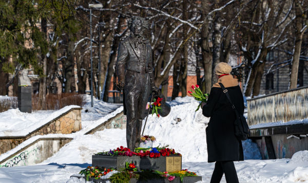 Женщина несет цветы к памятнику поэту Александру Сергеевичу Пушкину в парке Кронвалда в Риге, Латвия