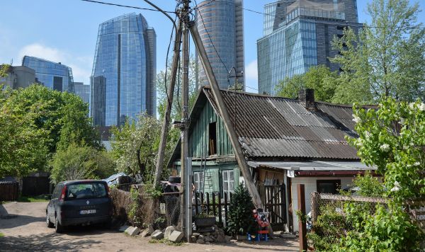 Деревянный частный дом на фоне небоскребов в деловом районе Вильнюса