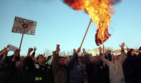 Сербские демонстранты сжигают американский флаг, протестуя против авиаударов НАТО по Югославии у посольства США в Скопье, 25 марта 1999 года