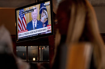 Люди смотрят выступление президента США Джо Байдена по телевизору