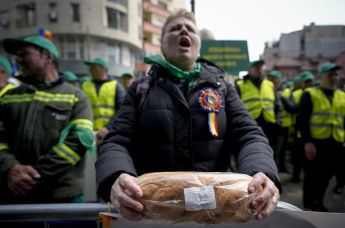 Женщина держит хлеб во время протестов фермеров напротив представительства Еврокомиссии в Бухаресте, Румыния, 7 апреля 2023 год