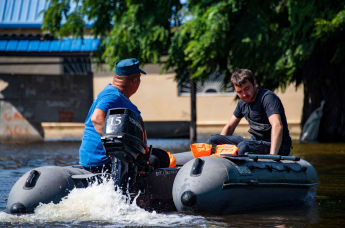 Мужчины плывут на лодке по селу Корсунка Новокаховского района Херсонской области, затопленному водой после разрушения Каховской ГЭС