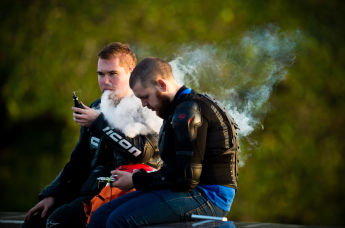 Молодые люди курят электронные сигареты