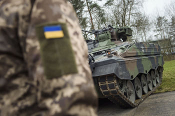 Украинский солдат стоит перед БМП