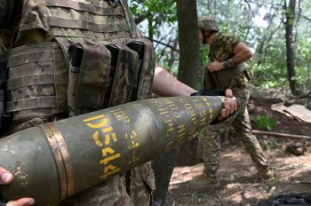Украинский артиллерист  держит155-мм снаряд для стрельбы из гаубицы M777