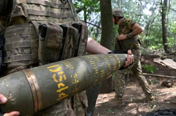 Украинский артиллерист  держит155-мм снаряд для стрельбы из гаубицы M777