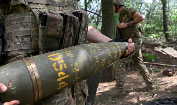 Украинский артиллерист  держит155-мм снаряд для стрельбы из гаубицы M777