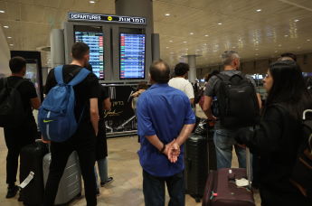 Пассажиры смотрят на табло вылета в аэропорту Бен-Гурион, Израиль, 7 октября 2023 года