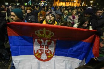 Мужчина держит флаг Сербии во время акции протеста в Белграде, 19 декабря 2023
