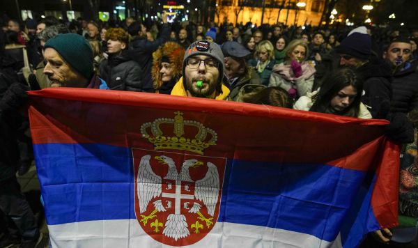 Мужчина держит флаг Сербии во время акции протеста в Белграде, 19 декабря 2023