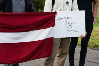 Плакат с надписью "Чемодан вокзал Россия ..." и флаг Латвии. Архивное фото