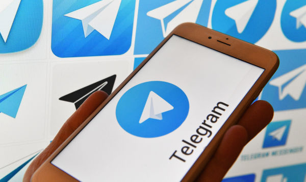 Логотип мессенджера Telegram на экранах смартфона и компьютера.