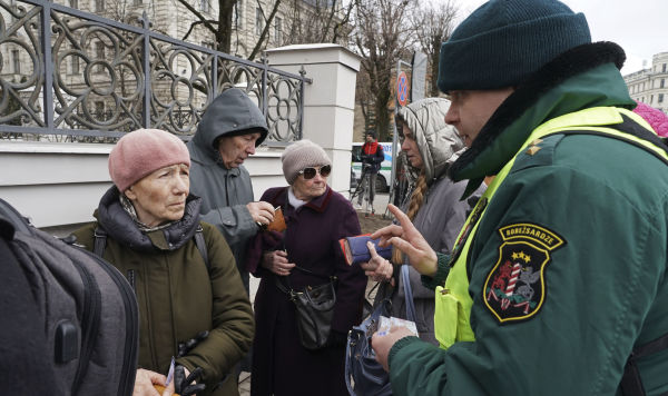 Латвийский пограничник проверяет документы у граждан России, проживающих в Латвии, которые пришли на избирательные участки в посольстве России для участия в президентских выборах в Риге, Латвия, воскресенье, 17 марта 2024 года.