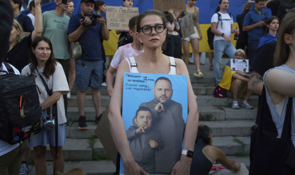 Протестующая держит в руках плакат с изображением президента Владимира Зеленского и главы Офиса Андрея Ермака