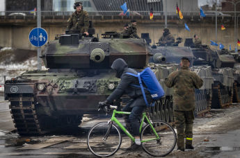 Велосипедист проезжает мимо основного боевого танка немецкой армии Leopard 2A6, припаркованного перед началом репетиции военного парада в честь 105-й годовщины Вооруженных сил Литвы в День Вооруженных сил в Вильнюсе, Литва, в пятницу, 24 ноября 2023 года.