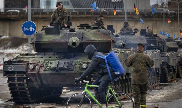 Велосипедист проезжает мимо основного боевого танка немецкой армии Leopard 2A6, припаркованного перед началом репетиции военного парада в честь 105-й годовщины Вооруженных сил Литвы в День Вооруженных сил в Вильнюсе, Литва, в пятницу, 24 ноября 2023 года.