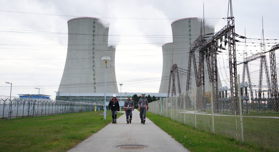 Рабочие проходят мимо градирен атомной электростанции Дукованы, Чехия, 21 октября 2025 года