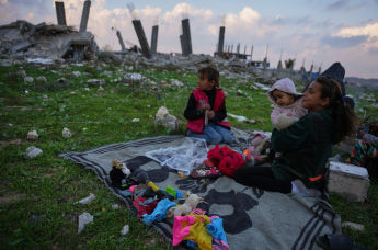 Семья на фоне разрушенных зданий в Нусейрате, центр сектора Газа