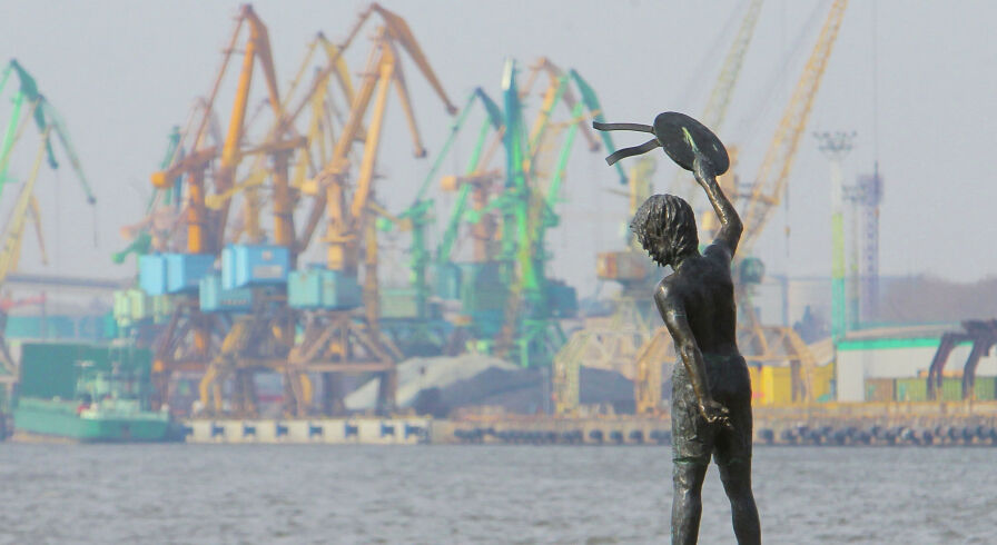 Памятник мальчику с бескозыркой и собакой, который провожает корабли в морском грузовом порту Клайпеды