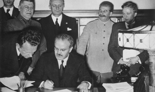 Вячеслав Молотов подписывает Договор о ненападении между Германией и Советским Союзом, за ним Иоахим Риббентроп, справа Иосиф Сталин, 23 сентября 1939 год