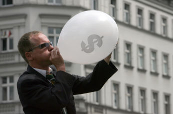 Человек в костюме надувает воздушный шар со значком американского доллара во время уличного шоу