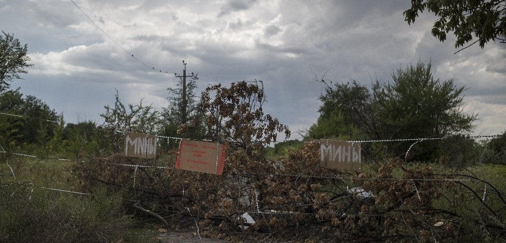 Забор с указателями "Мины" разрушенной средней школы украинского поселка Шахты 6/7, ставшей убежищем для местных жителей (Донбасс).