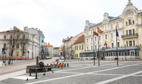 Старик кормит птиц на пустой площади в Старом городе Вильнюса, 29 марта 2020 года