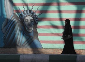 Женщина идет вдоль стены здания бывшего посольства США в Тегеране.